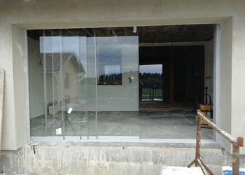 Bezrámové posuvné zasklení velkého vstupního otvoru vedoucího z rodinného domu na terasu